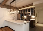 Thumbnail 8 of 23 - A modern kitchen with a white countertop and wooden floors.