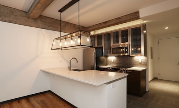 A modern kitchen with a white countertop and wooden floors.