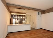 Thumbnail 7 of 23 - A kitchen area with a stainless steel range hood and wooden flooring.