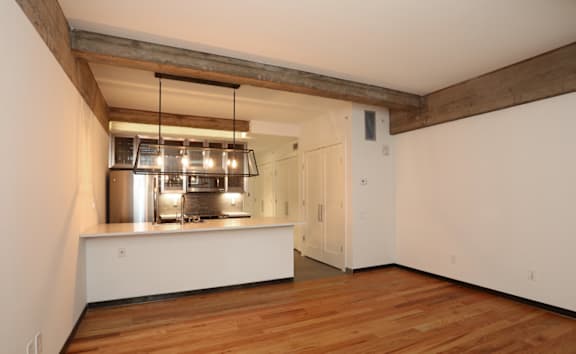 A kitchen area with a stainless steel range hood and wooden flooring.
