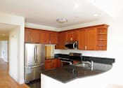Thumbnail 10 of 23 - A kitchen with wooden cabinets and a black countertop.