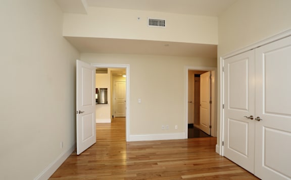 A room with white walls and wooden floors, with a door on the right side.