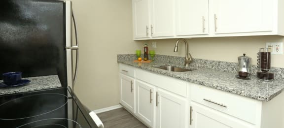Kitchen with vinyl flooring, granite countertops and white cabinets