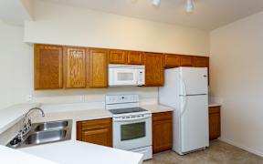 View of kitchen with oak cabinets and white appliances