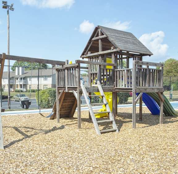A playground with a wooden swing set and a blue slide.