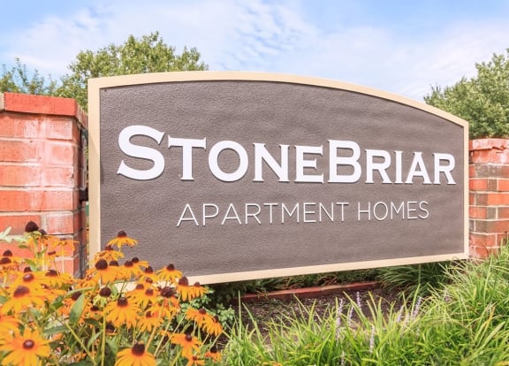a sign for stonebrae apartment homes in front of flowers