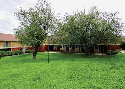 A grassy area in front of a building with trees.
