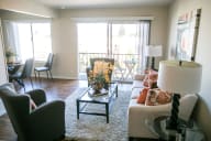 A living room with a glass coffee table and a white couch. at Three Crown Apartments, California, 94501