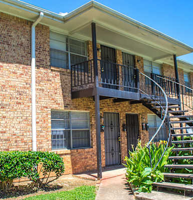 a spiral staircase leads to the front door of a brick building