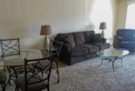 A living room with a grey couch, two chairs, and a glass table. at Waldo Heights, Missouri