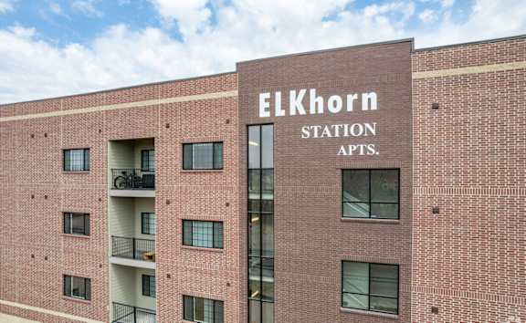 A red brick building with the words Elkhorn Station Apts. on the side.