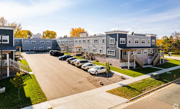 A row of houses with cars parked in front.