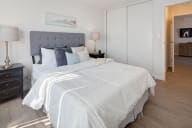 A bedroom with a large bed and a grey headboard. at Three Crown Apartments, California, 94501