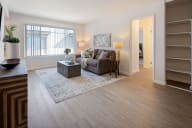 A living room with a grey couch, a wooden coffee table, and a rug. at Three Crown Apartments, California, 94501