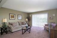 A living room with a couch, a coffee table, and a side table with a lamp. at Lansing Riverwood, LLC, Lansing, 60438