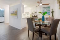 A dining room with a table and chairs and a poster on the wall. at Marine View Apartments, Alameda, CA