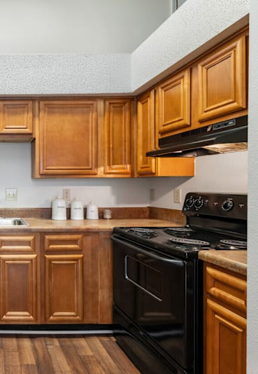 A kitchen with wooden cabinets and black appliances.