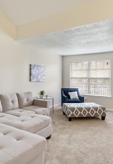 A living room with a white couch and a patterned ottoman.