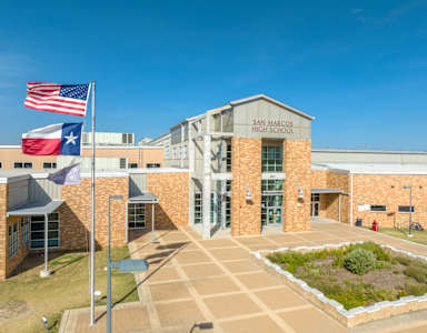 San Marcos High School is a large building with a flag flying in front.