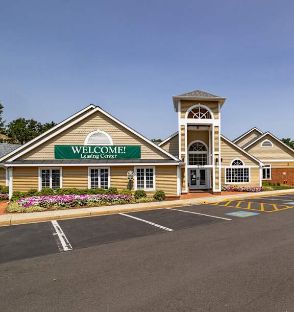A building with a sign that says "Welcome! Learning Center" in front of a parking lot.