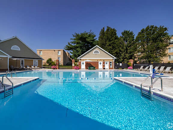 A large swimming pool in front of a building with a pool house.