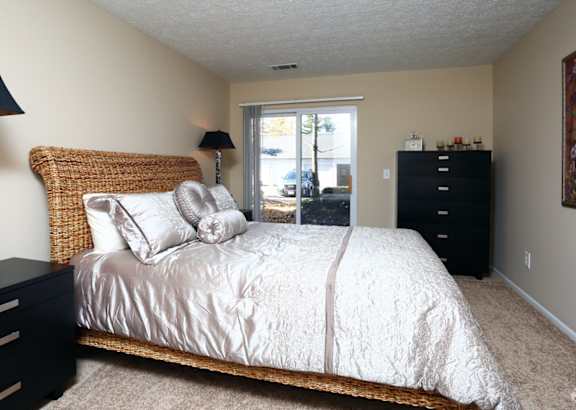 A bedroom with a bed, nightstand, and lamp.