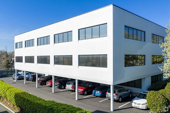 A white building with a parking lot in front.
