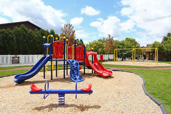 A playground with a blue slide and red and yellow slides.
