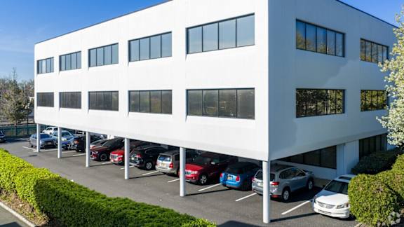A white building with a parking lot in front.