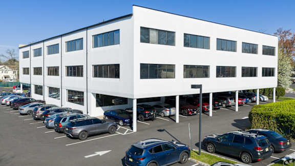 A white building with a parking lot in front of it.