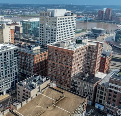 A cityscape with a mix of modern and older buildings, a tennis court, and a river in the distance.