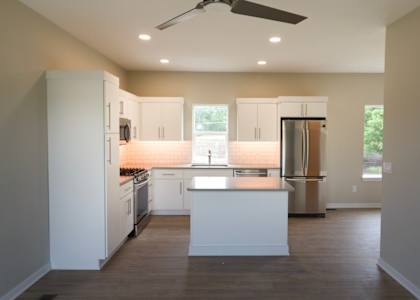 A modern kitchen with white cabinets and stainless steel appliances.