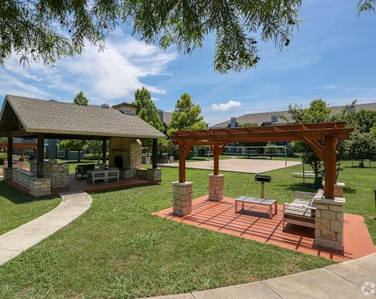 A gazebo is surrounded by a brick patio and a stone wall.