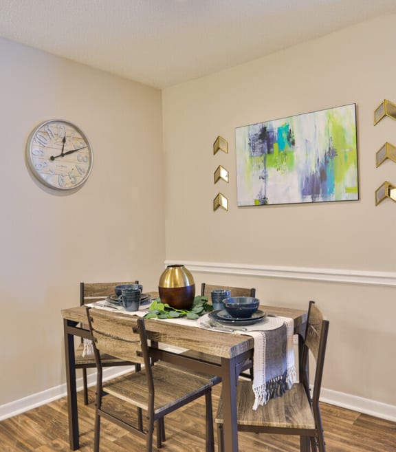 A dining room with a table set for two and a clock on the wall. at Magnolia Terrace Apartments, Charlotte, NC, 28213