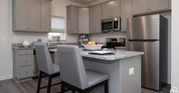 A kitchen with a refrigerator, microwave, and oven.