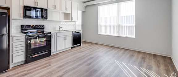 a kitchen with white cabinets and black appliances and a window