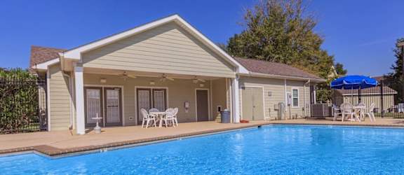 A house with a blue pool in front.