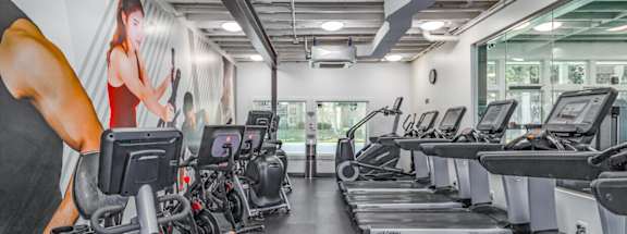 A gym with treadmills and a woman on the wall.