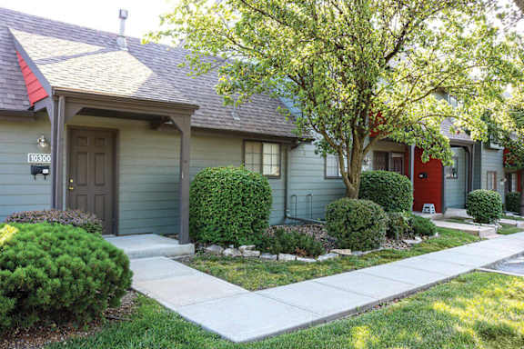 A house with a red door and a tree in front.