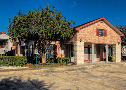 A red brick house with a tree in front.