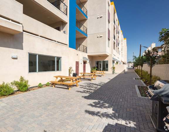an outdoor patio with picnic tables and barbecue grill