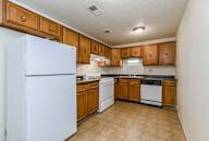 A kitchen with white appliances and wooden cabinets. at Waldo Heights, Kansas City, 64131