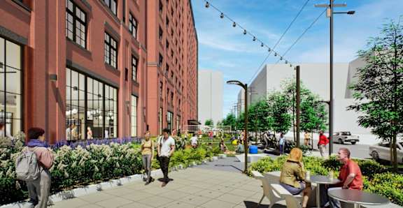 A street view with people walking and sitting on benches.