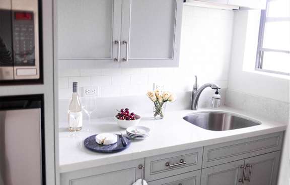 A kitchen with a white countertop and grey cabinets.