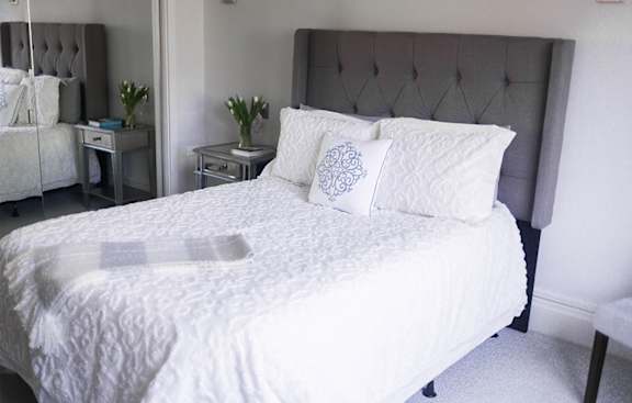 A bed with a white comforter and two decorative pillows.