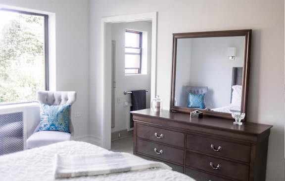 A bedroom with a bed, dresser, and mirror.