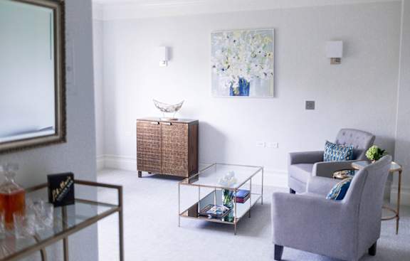 A living room with a grey armchair and a glass coffee table.