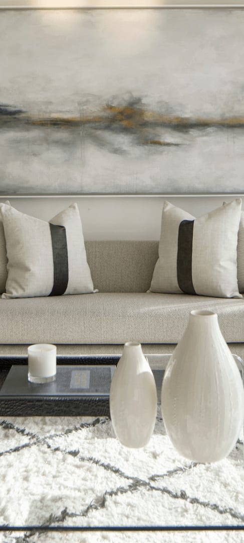 A living room with a couch, a coffee table, and a painting on the wall.