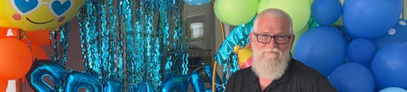A man stands in front of a balloon arch with the word "SPACE" on it.