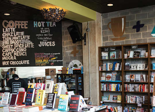 A woman is reading a book in a bookstore with a variety of books on display.
